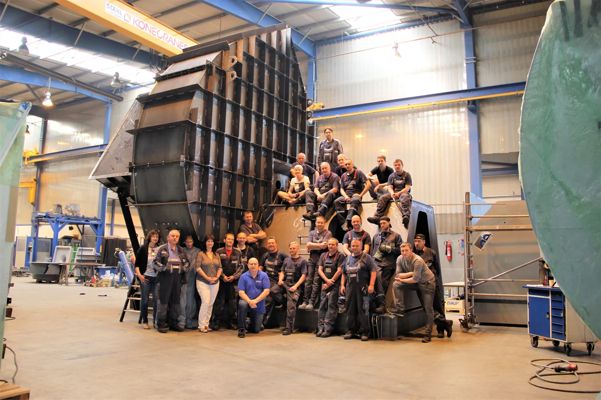 Il team di ingegneria e produzione di TunnelTech posa con orgoglio davanti a un imponente alloggiamento per ventilatore in acciaio nel nostro stabilimento di produzione a Stoccarda, in Germania. Questa struttura monumentale evidenzia le nostre ampie capacità di produzione interna e l'enorme scala dei nostri componenti per gallerie del vento ad alte prestazioni. Progettati con un'intransigente precisione tedesca, questi robusti sistemi aerodinamici garantiscono l'eccezionale affidabilità richiesta dalle nostre strutture di paracadutismo indoor delle serie PRO e SMART in tutto il mondo.