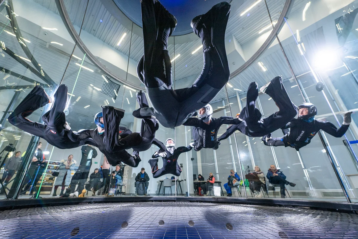 Profesionálny tím trénuje manévre relative work v letovej komore TT52 Pro v Kuzbas Arene. Komora s priemerom 5,2 metra poskytuje dostatok priestoru pre veľké skupiny a pokročilý tréning. Viditeľná je bezpečnostná sieť z oceľových lán s nízkym odporom a bezrámové steny z viacvrstvového skla. Diváci môžu vďaka kruhovému dizajnu skla sledovať tréning z vonkajšej strany s dokonalou viditeľnosťou.