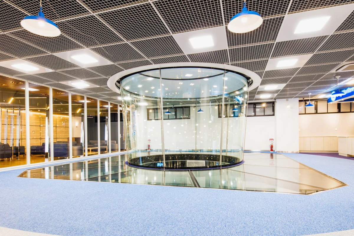 Het interieur van de FlyStation Japan faciliteit beschikt over een TunnelTech TT45 PRO windtunnel. De vliegruimte maakt gebruik van rond, meerlaags geluidsabsorberend glas om de luchtstroom te omsluiten en tegelijkertijd het zicht te maximaliseren. Een beloopbare structurele glazen vloer omringt de basis van de kamer, waardoor de technische apparatuur in de openbare ruimte wordt geïntegreerd. De omliggende ruimte omvat een receptie en met glas afgescheiden kijkruimtes onder een systeemplafond.