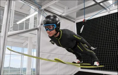 Close-up of a ski jumper in the aerial position with skis in the V-style, inside the Banana WS chamber