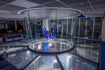 Two flyers performing head-down maneuvers in the TT45 PRO flight chamber at FlyStation Japan.
